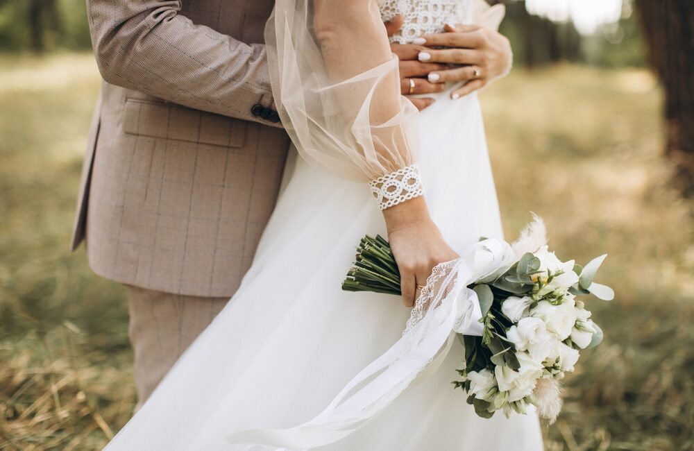 Braut und Bräutigam umarmend mit Brautstrauß am Hochzeitstag